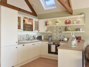 a kitchen with white cabinets and a skylight at Calf House Cottage in Sedgefield