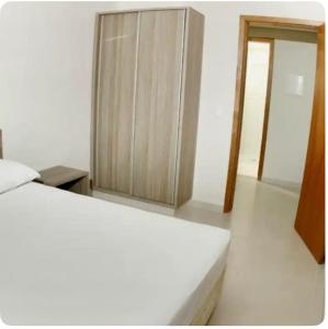 a bedroom with a white bed and a cabinet at Atrium Thermas Residence Service in Caldas Novas