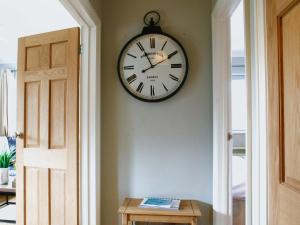 a clock hanging on a wall next to a door at Willow Cottage in Bentley
