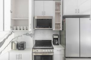 a white kitchen with a stove and a microwave at Blueground Midtown West wd nr Central Park NYC-1996 in New York