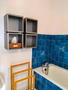 bagno piastrellato blu con vasca e lavandino di Joli appartement familial, 2 chambres, calme et soleil a Cabourg
