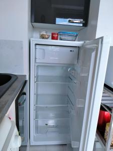un frigorifero vuoto con la porta aperta in una cucina di Joli appartement familial, 2 chambres, calme et soleil a Cabourg