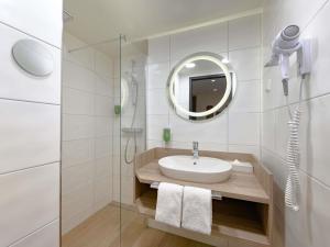 a white bathroom with a sink and a mirror at ibis Styles Kiel City in Kiel +84 photos