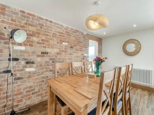 comedor con pared de ladrillo y mesa y sillas de madera en Heron's Den - Uk44529, en Horncastle
