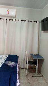 a bedroom with a bed and a table and a desk at Hotel Vale do Sol in Valparaíso