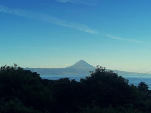a mountain in the distance with trees and water at Casa de Lá in Urzelina +9 photos
