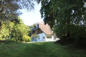 a white house on a green hill with trees at Haus Koppelweg FW-Fisch in Ahrenshoop