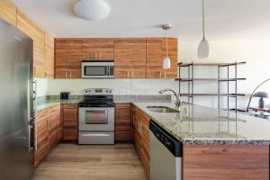 a kitchen with wooden cabinets and stainless steel appliances at Blueground Brighton fitness center nr Park SEA-876 in Seattle +26 photos