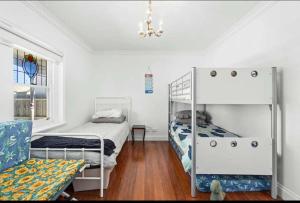 a bedroom with two bunk beds and a chair at Mini Beach Cottage - Seaspray Escape in Seaspray