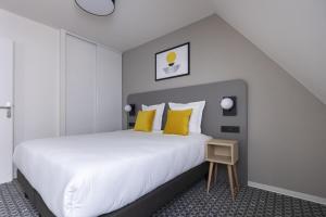 a bedroom with a large white bed with yellow pillows at Appart'hôtel Odalys City - Strasbourg Centre Les Halles in Strasbourg