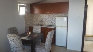 a kitchen with a table and a refrigerator and chairs at Apartments Diva in Dobra Voda