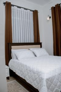 a bed with white sheets and pillows in a bedroom at Reza stays apartment -Makumbusho behind Mwanga Tower in Dar es Salaam
