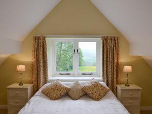 Un dormitorio con una cama blanca y una ventana. en Winhill Cottage, en Bamford