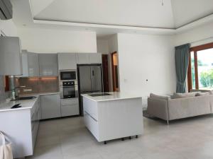 a kitchen with white cabinets and a couch in a room at Hana 4 in Ban Nong Chaeng
