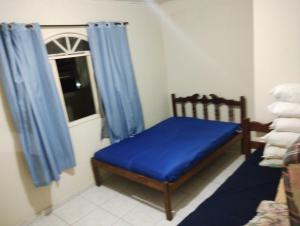 a small room with a blue bed and a window at Casa Faé in Guarapari