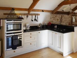 Una cocina con gabinetes blancos y un horno de estufa. en The Stables By The Sea, en Newquay