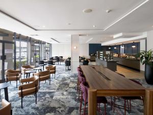 a restaurant with a large wooden table and chairs at Mercure Brisbane Garden City in Brisbane