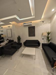 a living room with black couches and a table at فندق قربان in Al Madinah