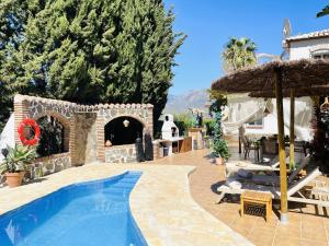a patio with a swimming pool and an umbrella at Villa Jina con piscina by At Home Costa del Sol in Torrox