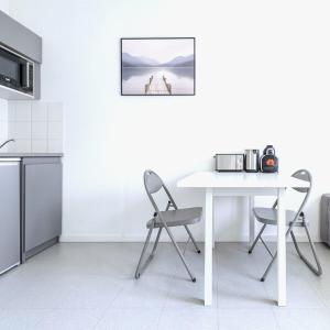 a white kitchen with a white table and chairs at Small functional cocoon Ideal solution for students or professionals in Vaise