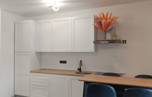 a kitchen with white cabinets and a table with blue chairs at 2 Bedroom Awesome Apartment In Seline in Jurlina