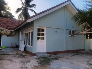 a white building with a door and a palm tree at Delft Samudra Hotel in Jaffna +17 photos