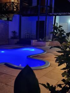 a blue swimming pool in a backyard at night at Pousada Petit - aluguel quartos in Aracati