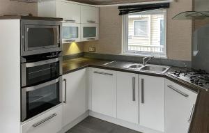 a kitchen with white cabinets and a sink and a microwave at 2 Bedroom Cozy Home In Lindesnes in Spangereid