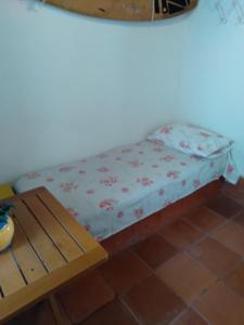 a small bed in a room with a wooden table at Quarto Duplo, Casa da Jô in Angra dos Reis