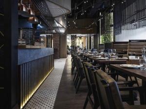 a dining room with wooden tables and chairs at Novotel Living Almaty Jetisu in Almaty