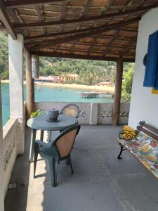 a table and chairs on a patio with a view of the water at Quarto Duplo, Casa da Jô in Angra dos Reis