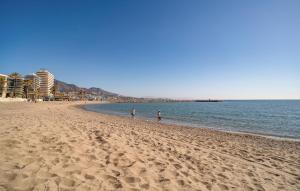 two people walking on a beach near the water at Beautiful Home In Fuengirola With Wifi in Fuengirola
