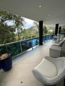 a balcony of a house with a table and chairs at Toninhas Beach - Gated Community - Ubatuba-SP in Ubatuba +57 photos