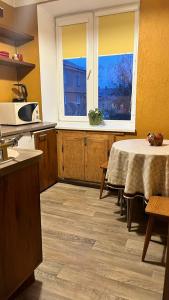een keuken met een tafel en twee ramen en een tafel bij Imantas in Daugavpils