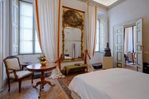 a bedroom with a bed and a table and a mirror at Palazzo Giacometti Suites in Piacenza