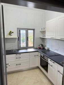 a kitchen with white cabinets and black counter tops at SunHome Ismailaj in Poliçan