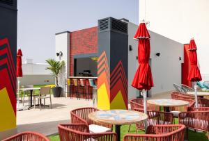 an outdoor patio with tables and chairs and red umbrellas at Sholeo Lodges Las Palmas Flats in Las Palmas de Gran Canaria