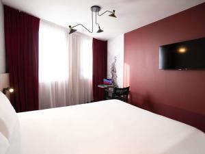 a bedroom with a white bed and a tv on the wall at ibis Styles Lens Centre Gare in Lens
