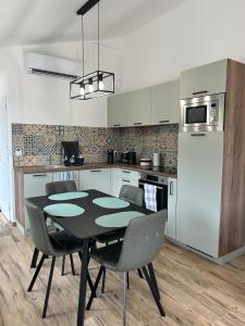 a kitchen with a black table and chairs and a refrigerator at Les gites saint Laurent - l'élégante in Mouy