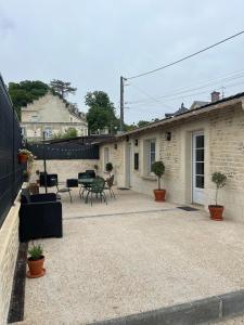 a patio with a table and chairs and a building at Les gites saint Laurent - l'élégante in Mouy +4 photos
