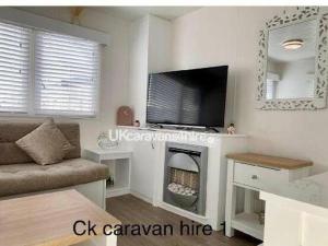 a living room with a tv and a fireplace at Golden Gate Holiday Centre - Holiday Accommodation 19058 in Kinmel Bay +4 photos