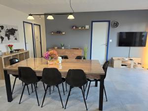 une table de salle à manger avec des chaises noires et une télévision dans l'établissement Ti Goéland 4 chambres Proche Mont St Michel, à Roz-sur-Couesnon