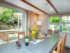 a dining room with a table with flowers and wine bottles at The Farm House in Porkellis