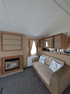 a living room with a couch and a fireplace at Camber Sands Holiday Park - Holiday Accommodation 21210 in Camber