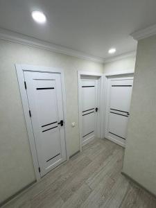 three white doors in a room with wood floors at Panorama view apartament tolstoi str in Chişinău