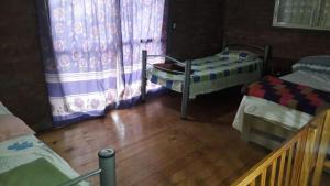 a room with two beds and a wooden floor at El Carau Alquileres in Paso de la Patria