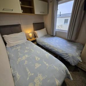 two beds in a small room with a window at Thornwick Bay Holiday Village - Holiday Accommodation 20633 in Flamborough