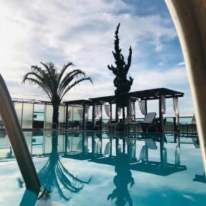 a pool with chairs and palm trees next to the ocean at Pousada Recanto da Fazenda in Pinhalzinho
