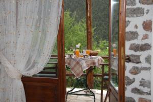 a table on a balcony with a view of a forest at Dryades Guesthouse in Ano Chora