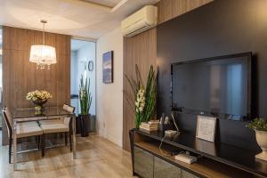 a living room with a large television and a dining table at Melhor Apartamento centro Pomerode, perto de tudo in Pomerode